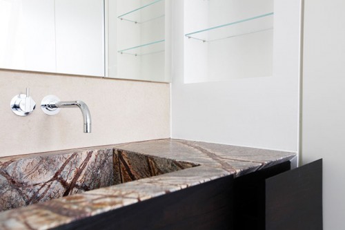 Waschtisch aus Naturstein, flächenbündiger Spiegelschrank.